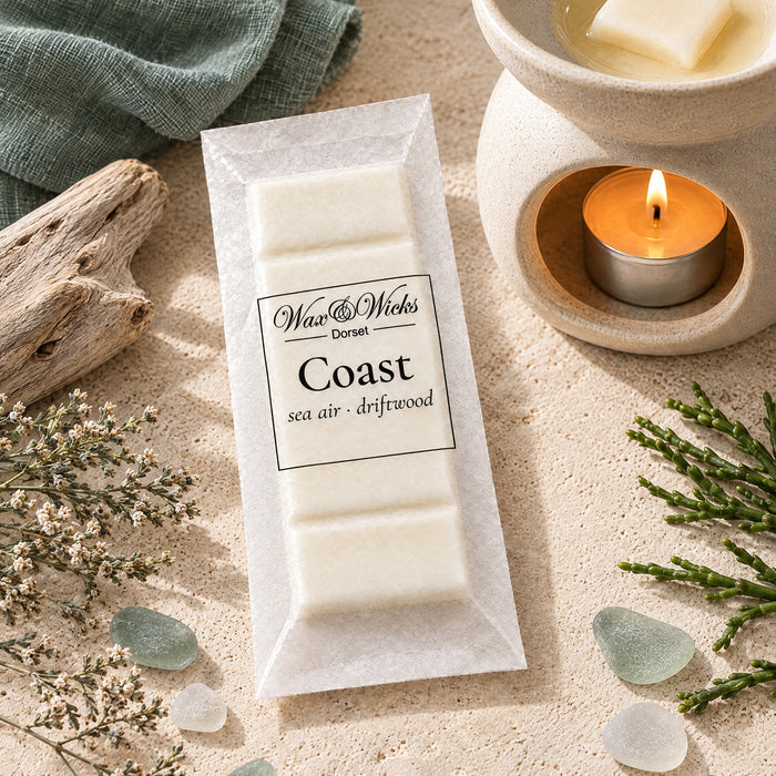Coast wax melt snap bar, beside a tea-light wax burner, styled with bleached driftwood, sea-glass pebbles, dried sea lavender and samphire