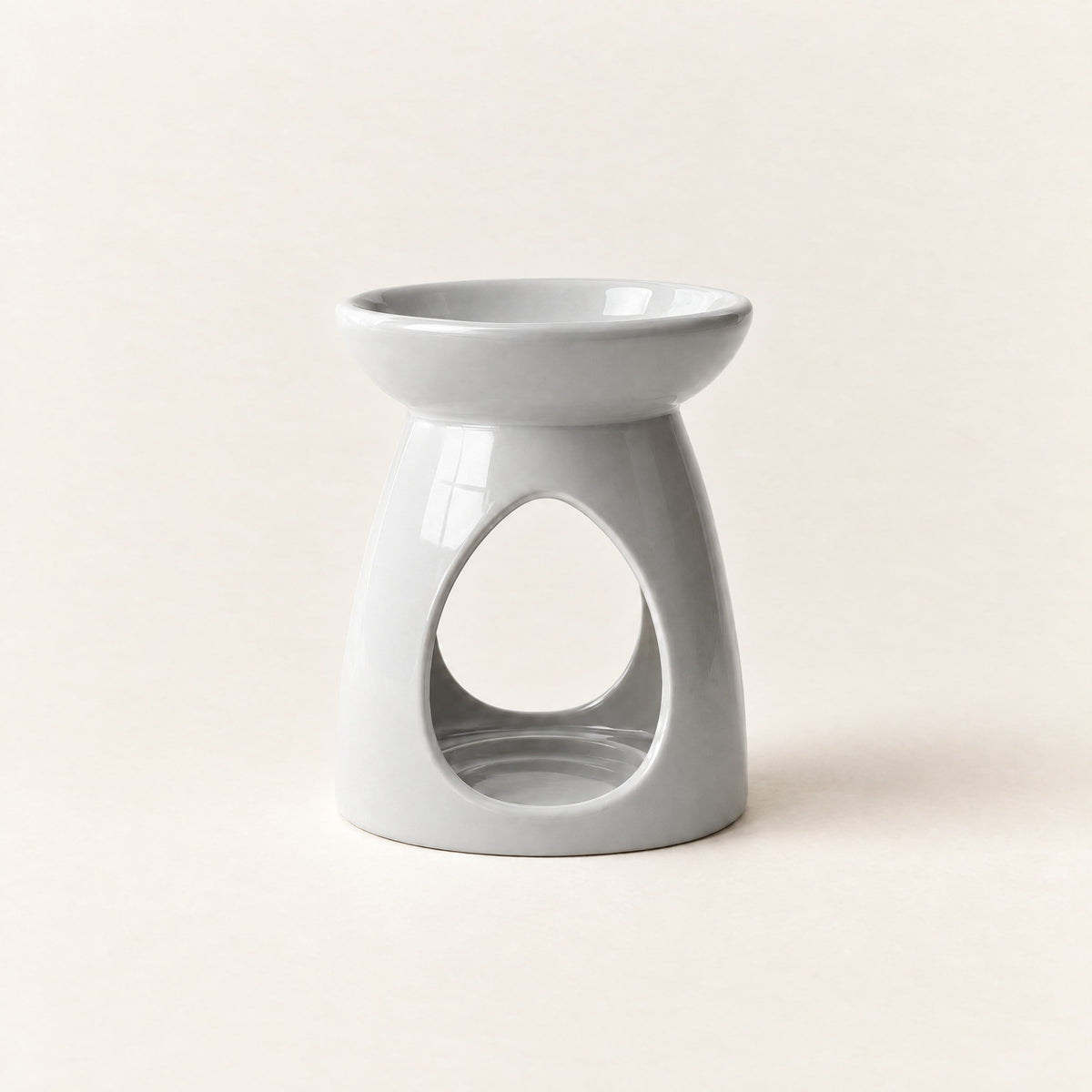Ceramic wax melt burner in pale grey, with a teardrop opening for a tea-light, on a plain ivory background