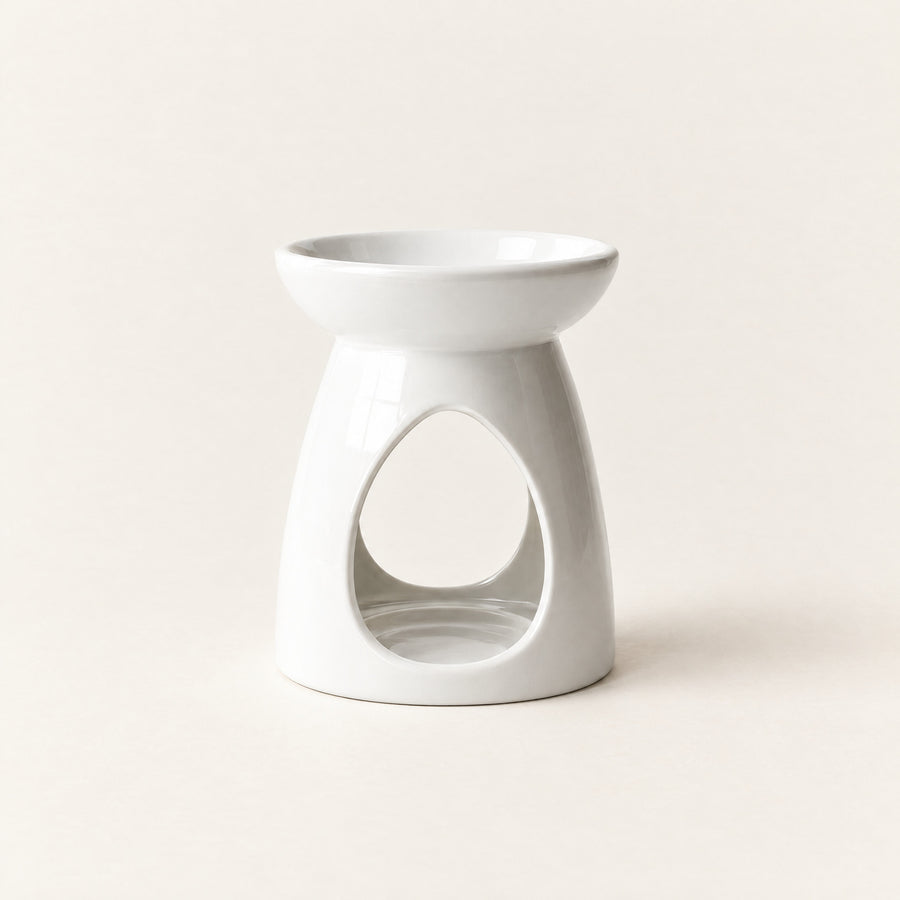 Ceramic wax melt burner in glossy white, with a teardrop opening for a tea-light, on a plain ivory background