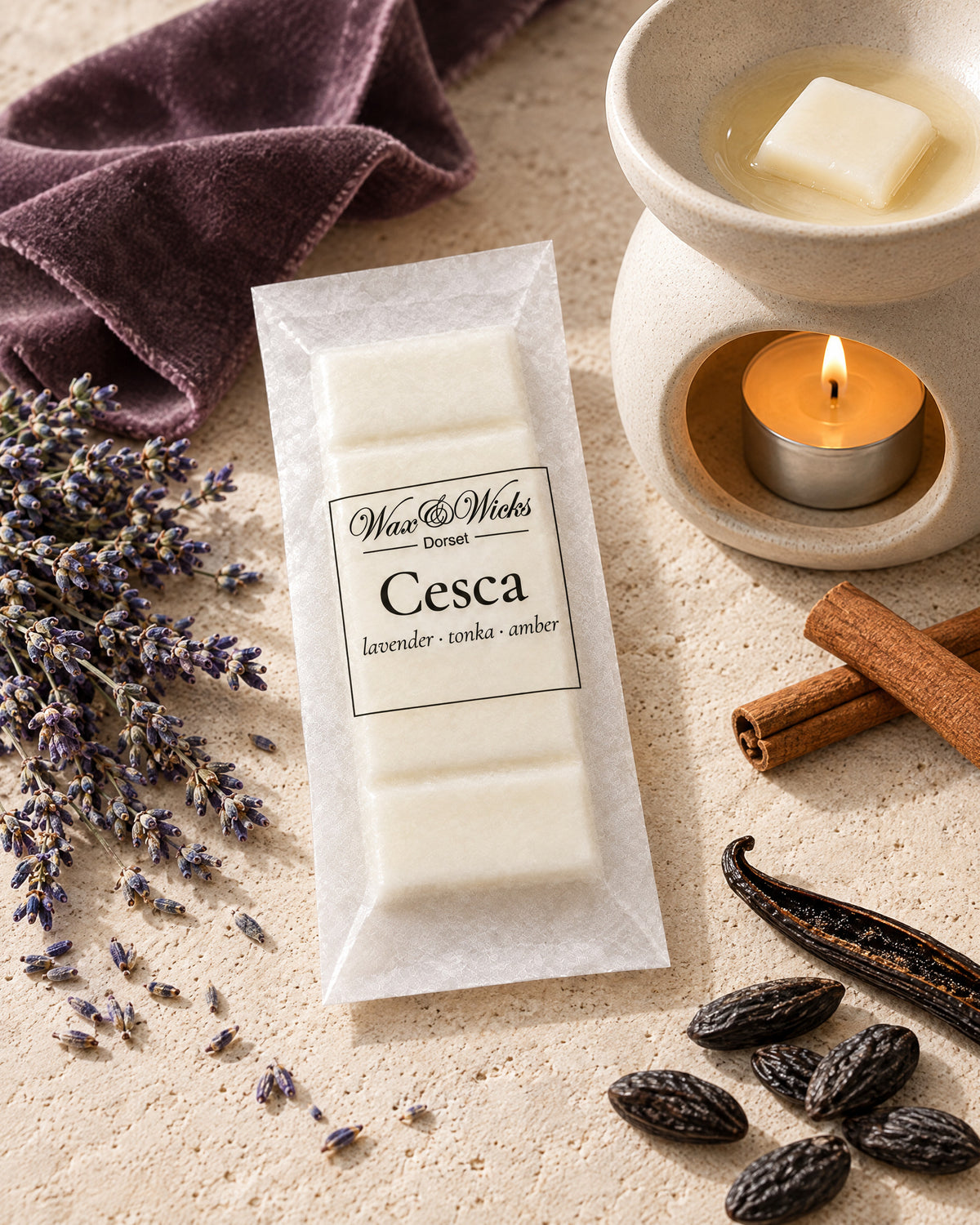 Cesca wax melt snap bar, beside a tea-light wax burner, styled with dried lavender, tonka beans, cinnamon sticks, a vanilla pod and amber resin