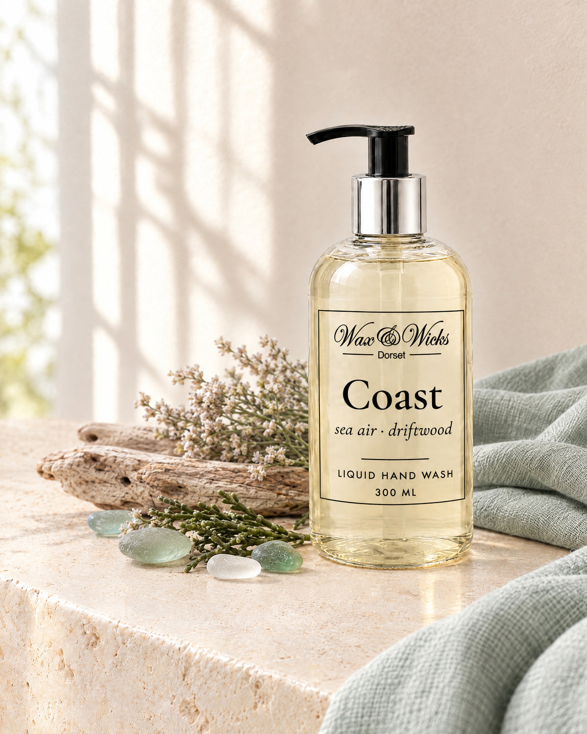 Coast liquid hand wash, 300 ml pump bottle, styled with bleached driftwood, sea-glass pebbles, dried sea lavender and samphire