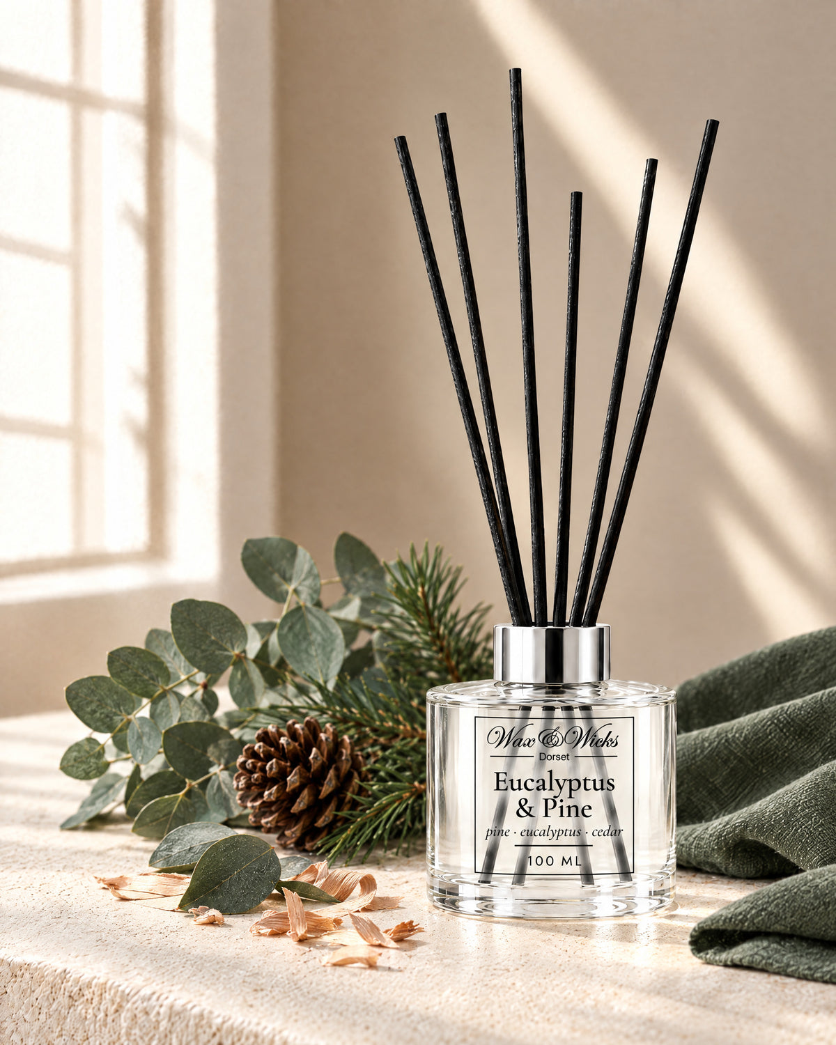 Eucalyptus & Pine 100 ml reed diffuser with black fibre reeds, styled with eucalyptus stems, pine sprigs, a pine cone and cedar shavings