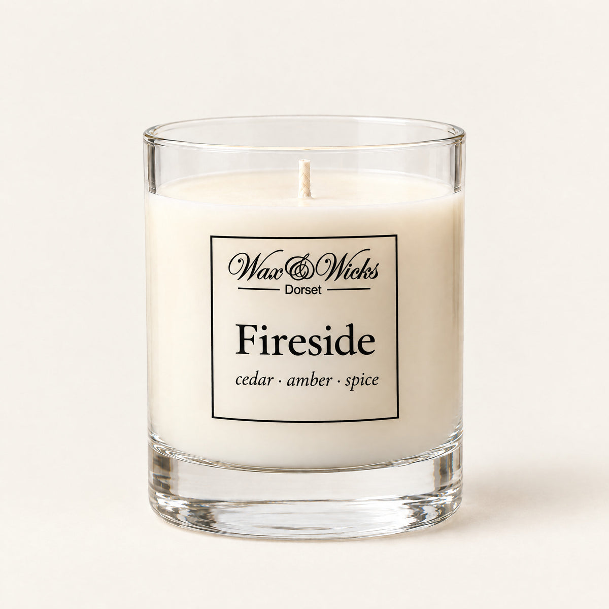 Small Fireside candle, one wick, in a clear glass jar, on a plain ivory background