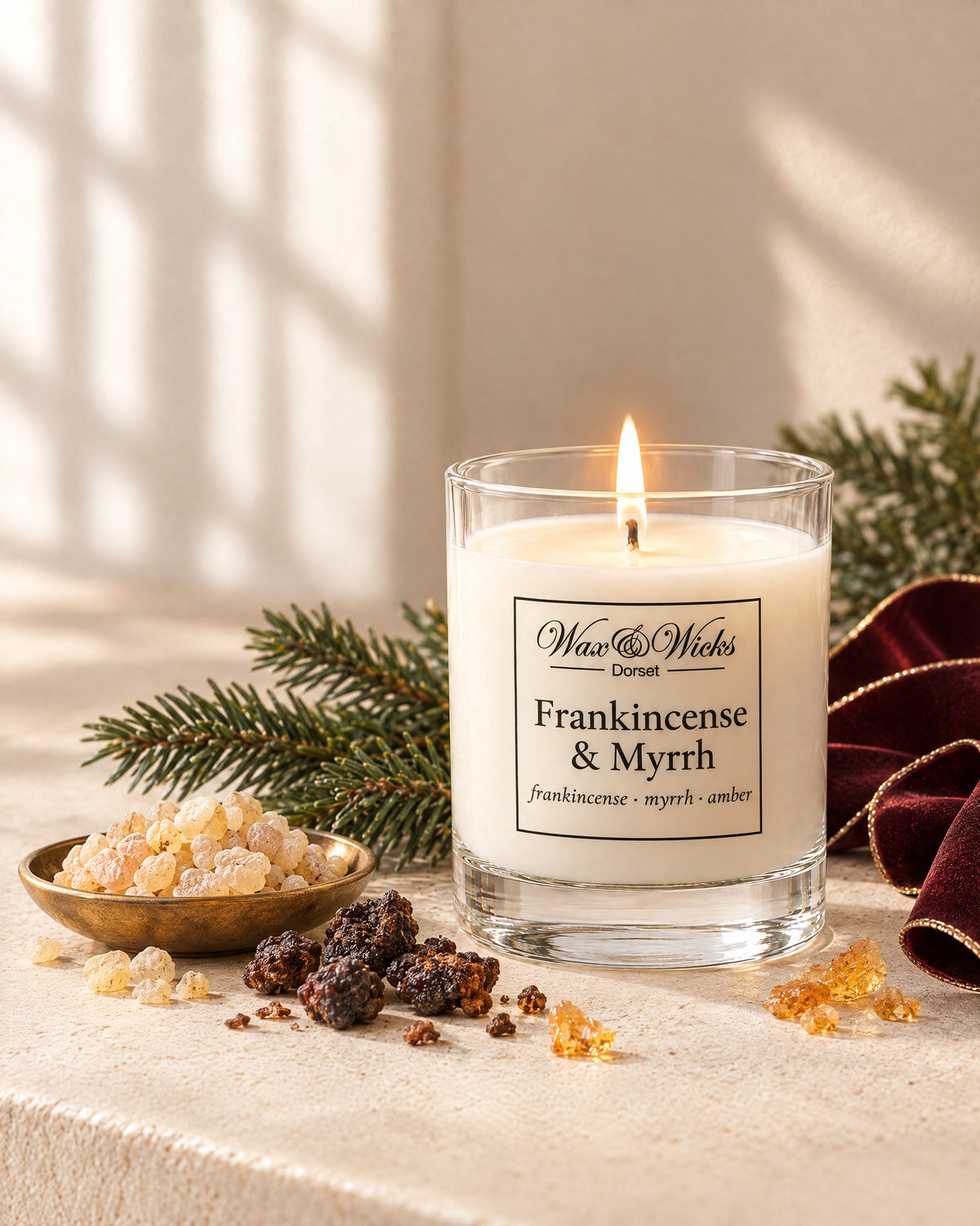 Small Frankincense & Myrrh candle, one wick, in a clear glass jar, styled with frankincense and myrrh resin, a fir sprig and burgundy ribbon