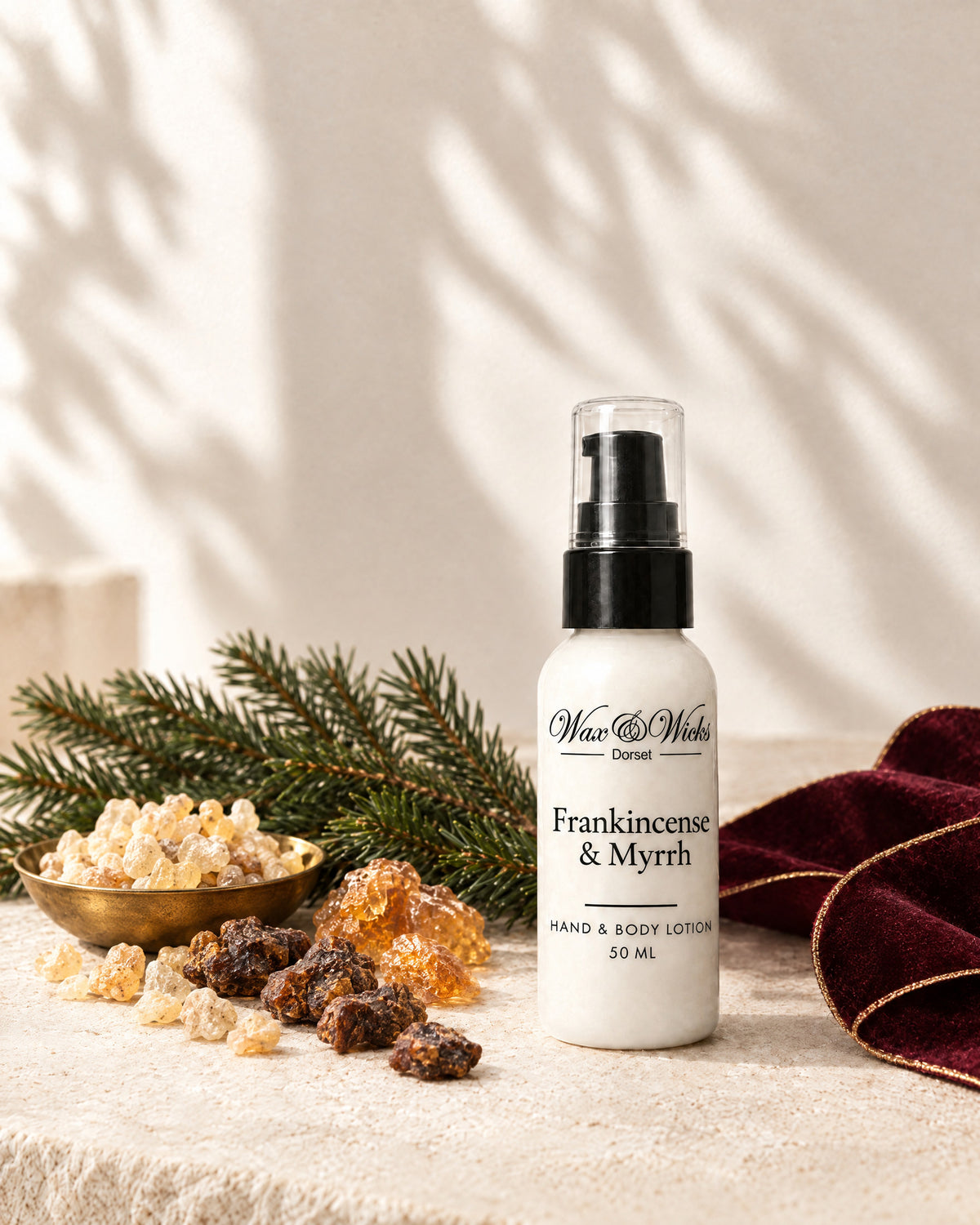 Frankincense & Myrrh hand & body lotion, 50 ml bottle, styled with frankincense and myrrh resin, a fir sprig and burgundy ribbon