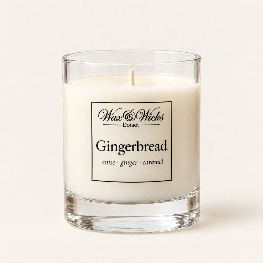 Small Gingerbread candle, one wick, in a clear glass jar, on a plain ivory background