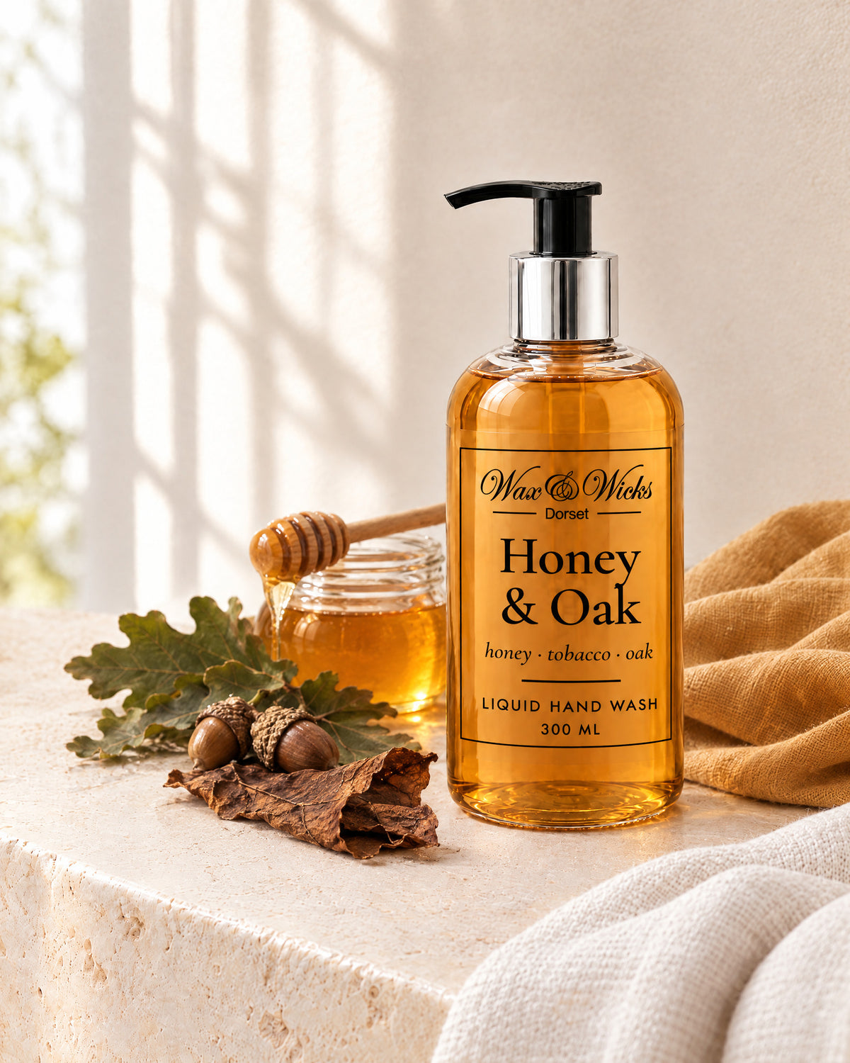 Honey & Oak liquid hand wash, 300 ml pump bottle, styled with a jar of honey, oak leaves, acorns and tobacco leaf