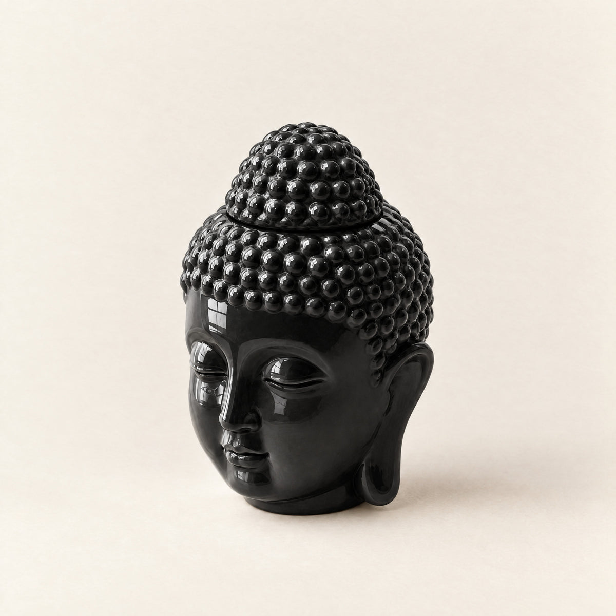 Prince Buddha wax melt burner in glossy black ceramic, a Buddha head with a top-knot lid, on a plain ivory background