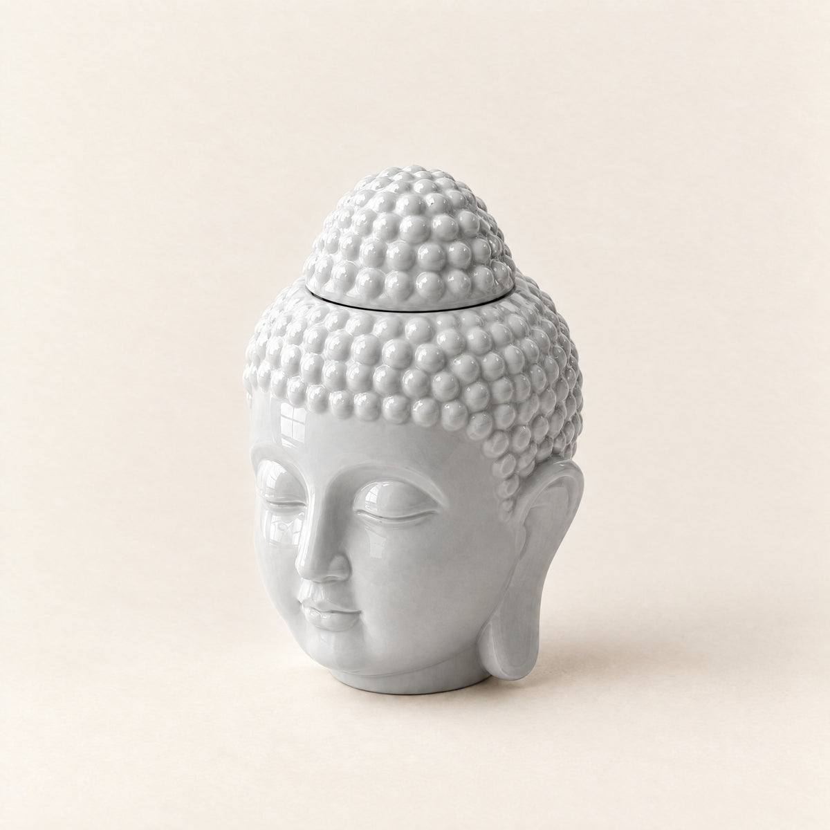 Prince Buddha wax melt burner in pale grey ceramic, a Buddha head with a top-knot lid, on a plain ivory background