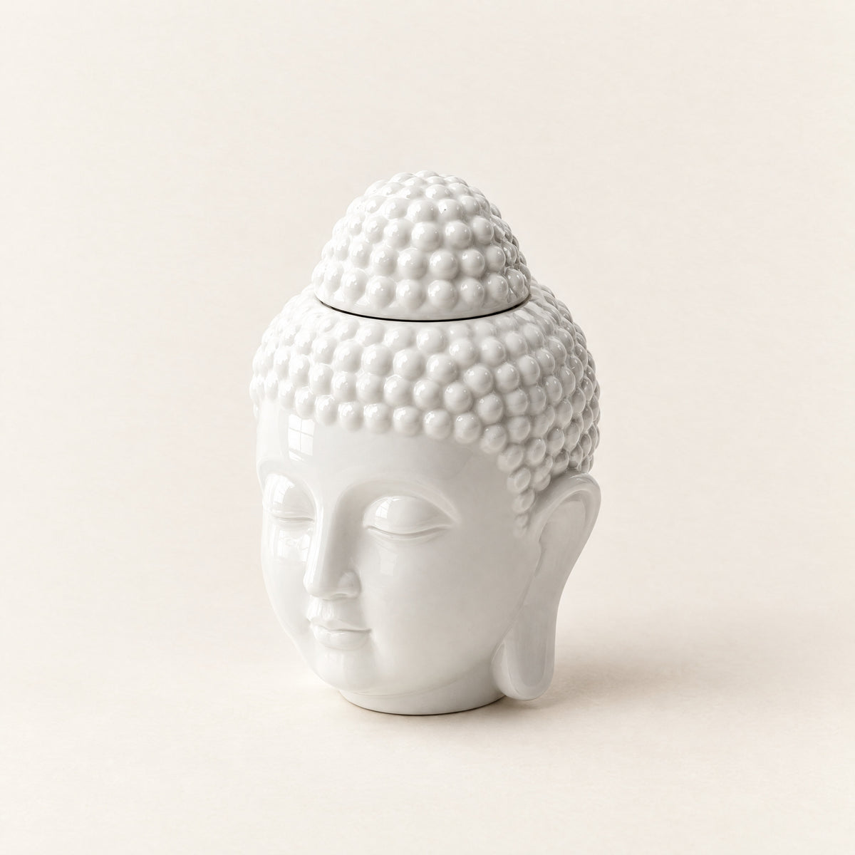 Prince Buddha wax melt burner in white ceramic, a Buddha head with a top-knot lid, on a plain ivory background