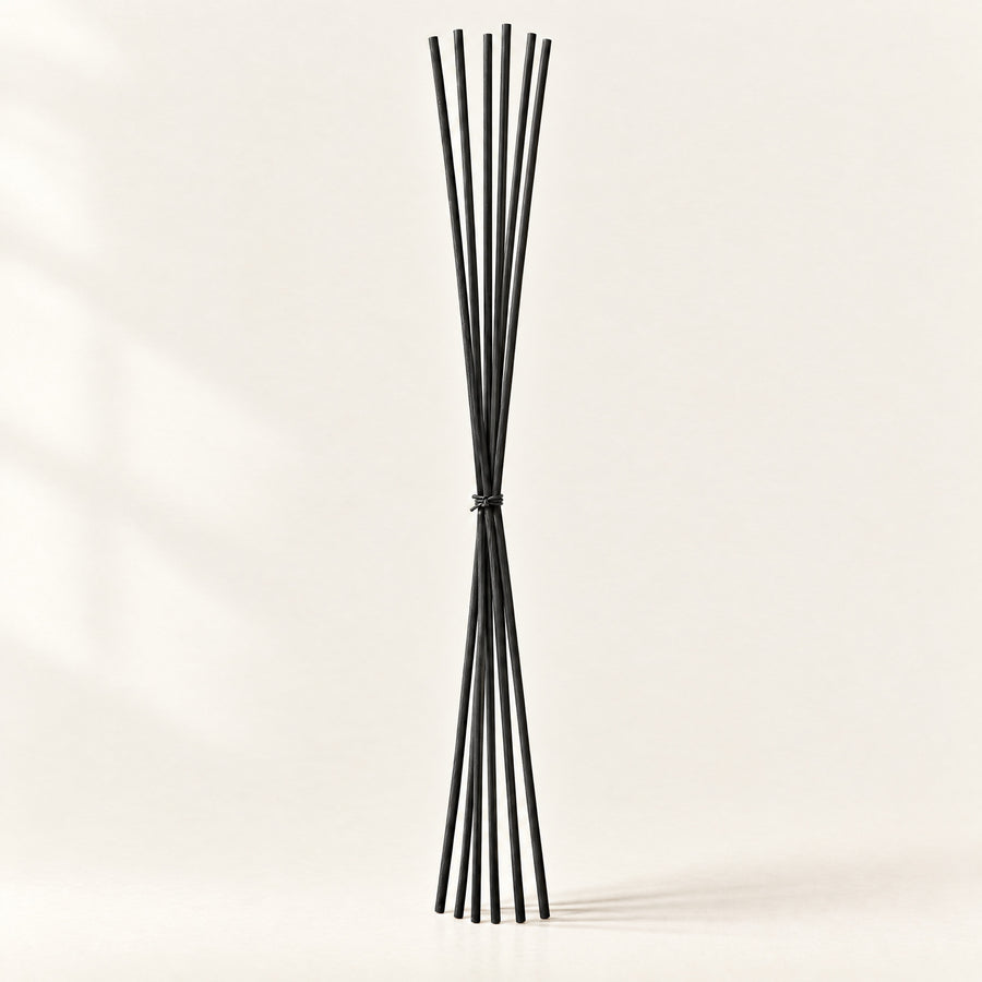 Bundle of extra-long black fibre replacement reeds tied with natural cord, standing on a plain ivory background