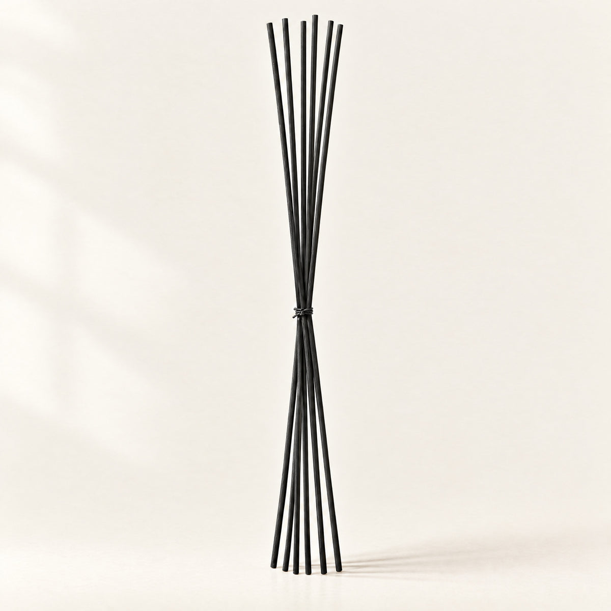Bundle of extra-long black fibre replacement reeds tied with natural cord, standing on a plain ivory background
