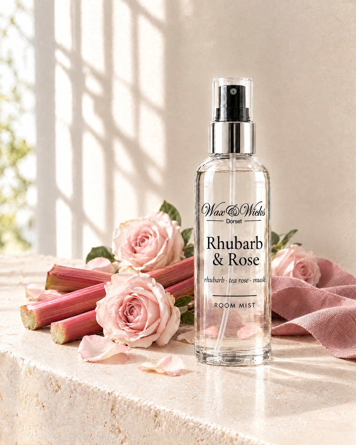 Rhubarb & Rose room mist, 100 ml spray bottle, styled with stalks of pink rhubarb, pale pink roses and rose petals, with a dusky pink linen