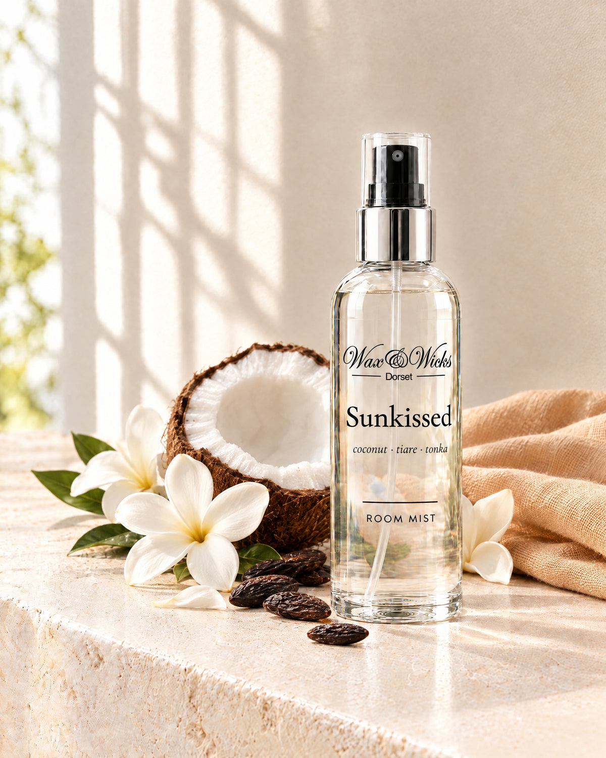 Sunkissed room mist, 100 ml spray bottle, styled with half a coconut, white tiare flowers and tonka beans, with a peach linen