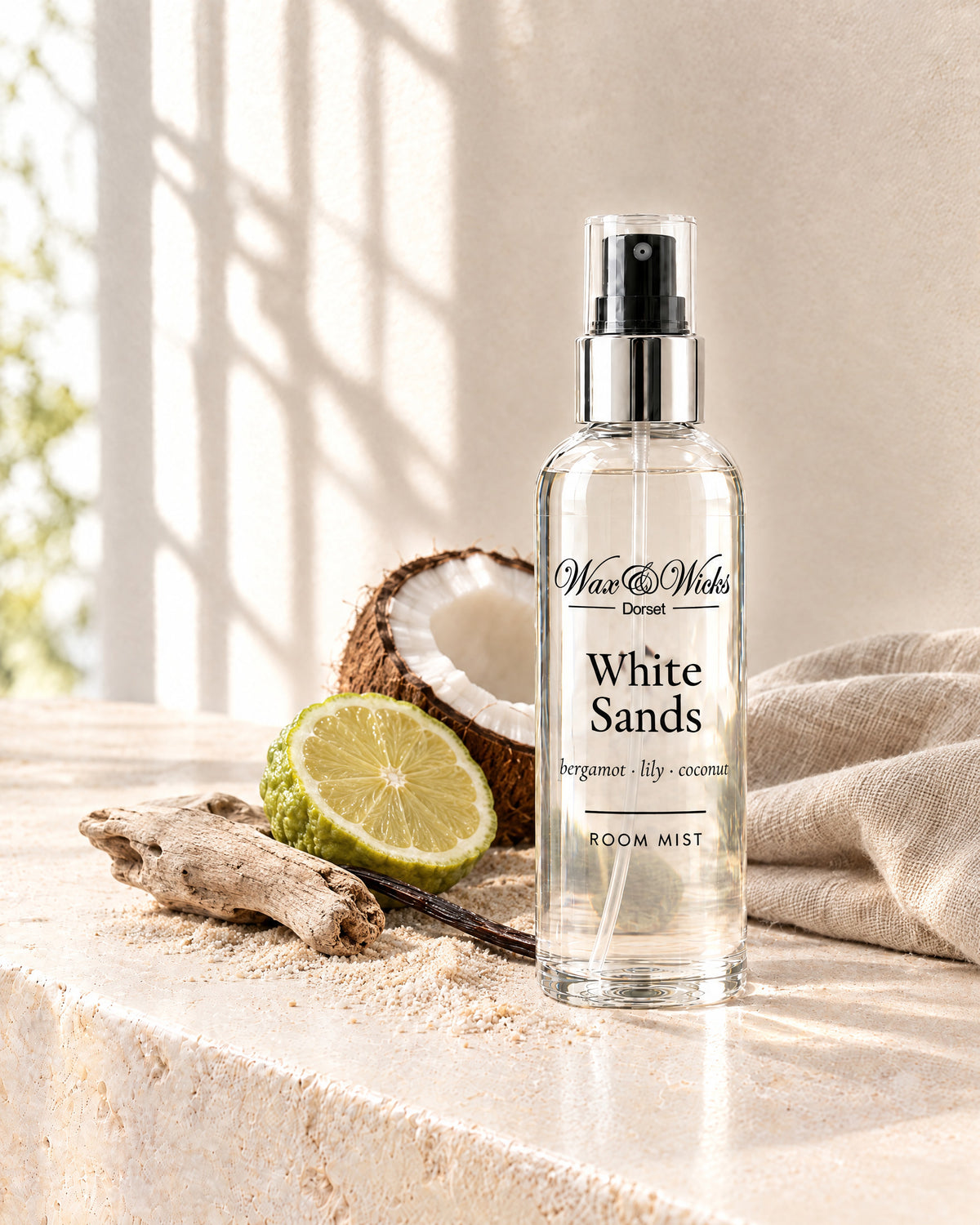 White Sands room mist, 100 ml spray bottle, styled with half a bergamot, half a coconut, a vanilla pod and driftwood on pale sand
