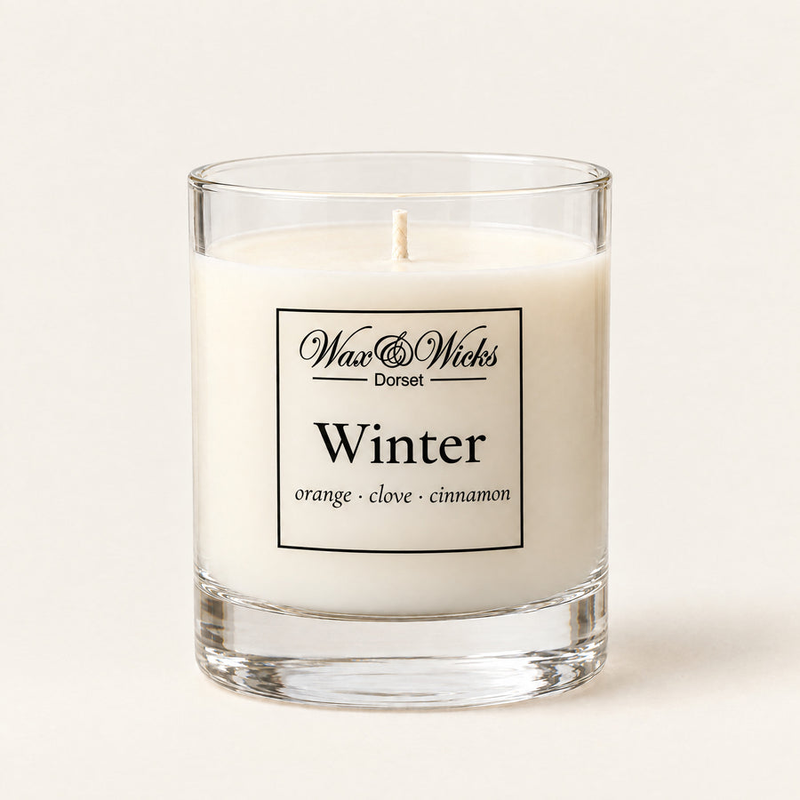 Small Winter candle, one wick, in a clear glass jar, on a plain ivory background